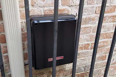 Automatic gate opener installed on side of house.