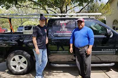 Garage door repair workers next to truck.
