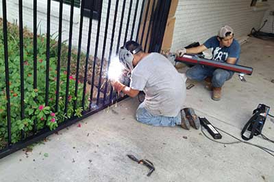 Gate repair men welding an iron gate.