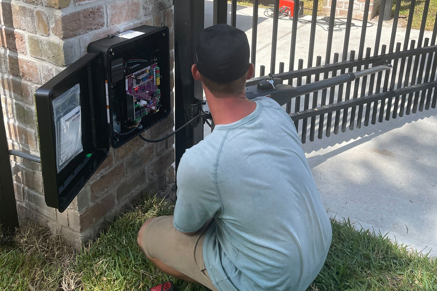 Gate repair technician from Sentry Garage Door & Gates fixing a LiftMaster driveway gate opener.