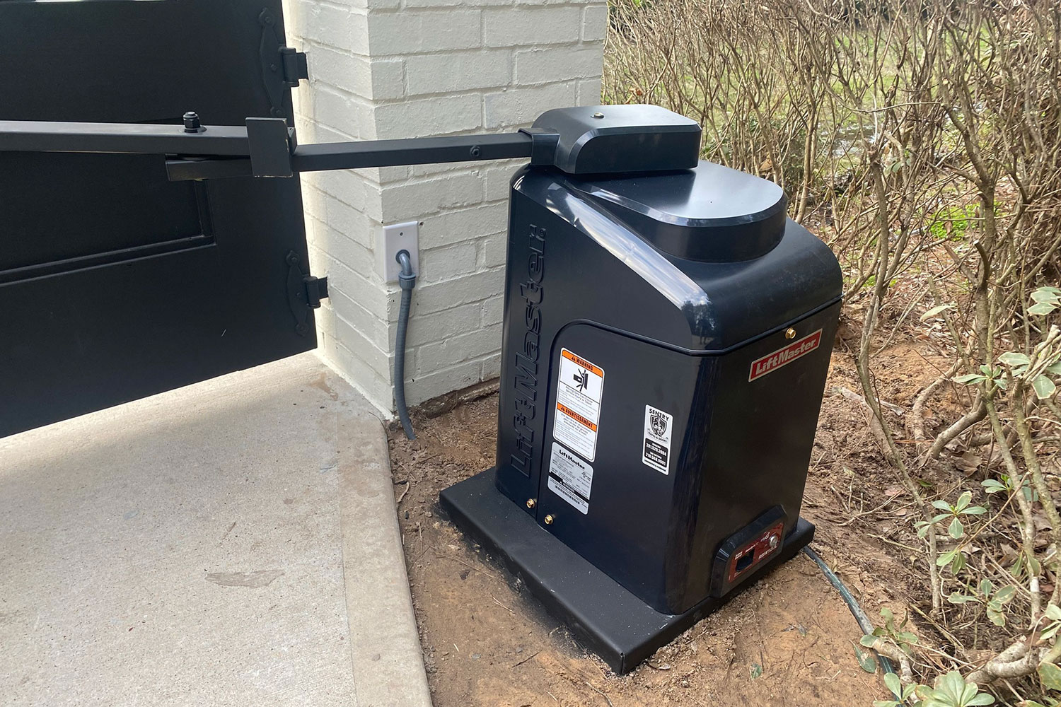 Close up pic of a LiftMaster swing driveway gate opener installed by Sentry in Houston, TX.